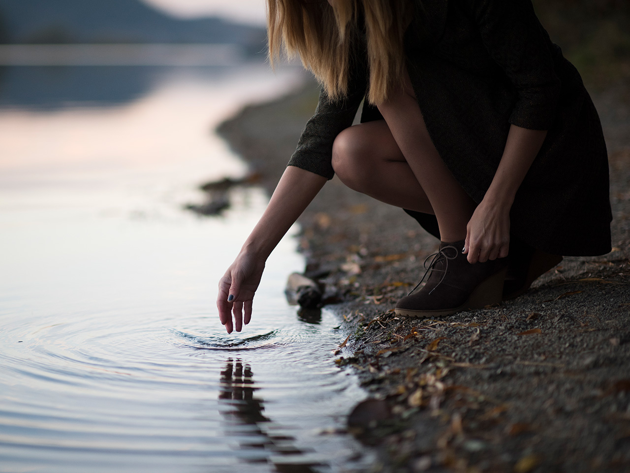 fashion-05 Woman on a river bank stooping down to touch the water